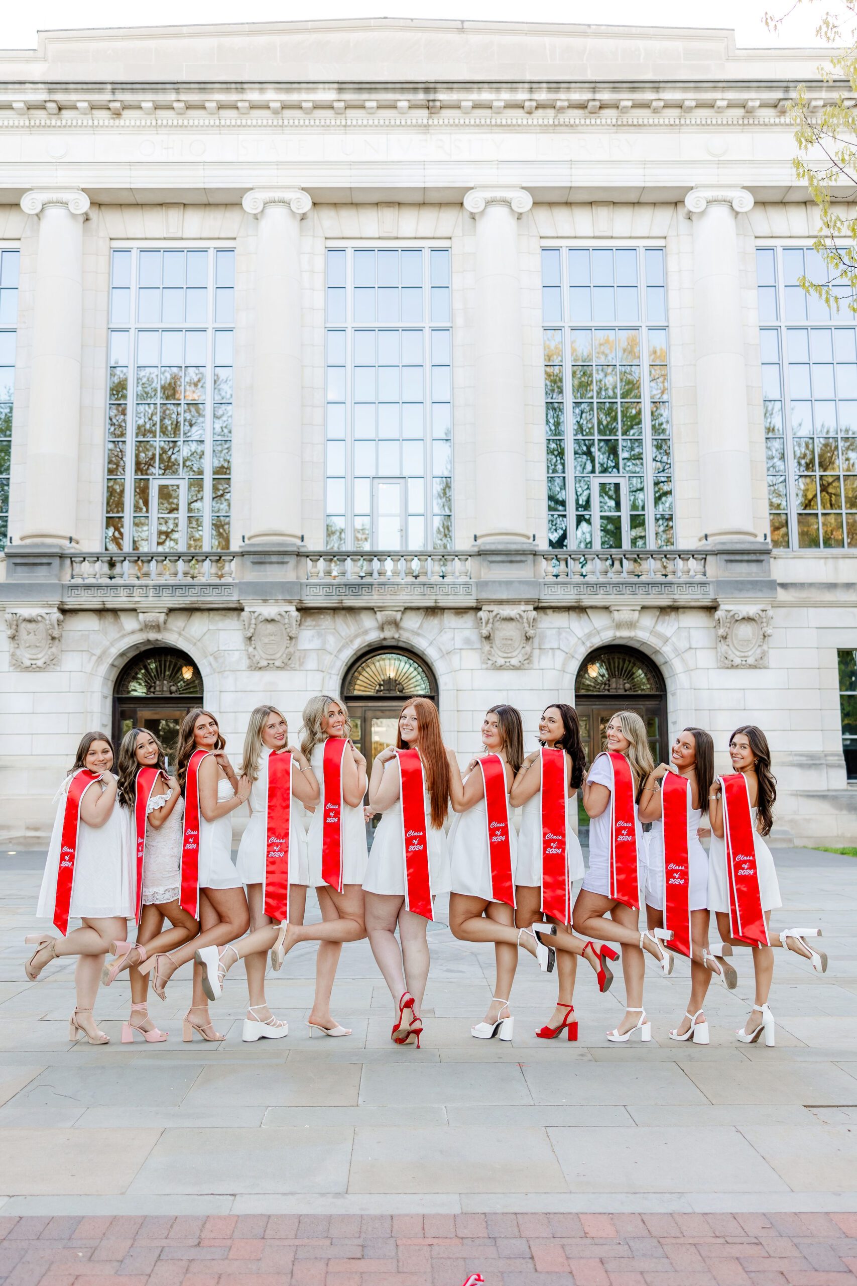 Group of OSU seniors in cap and gown at Thompson Statue, Ohio State graduation photo